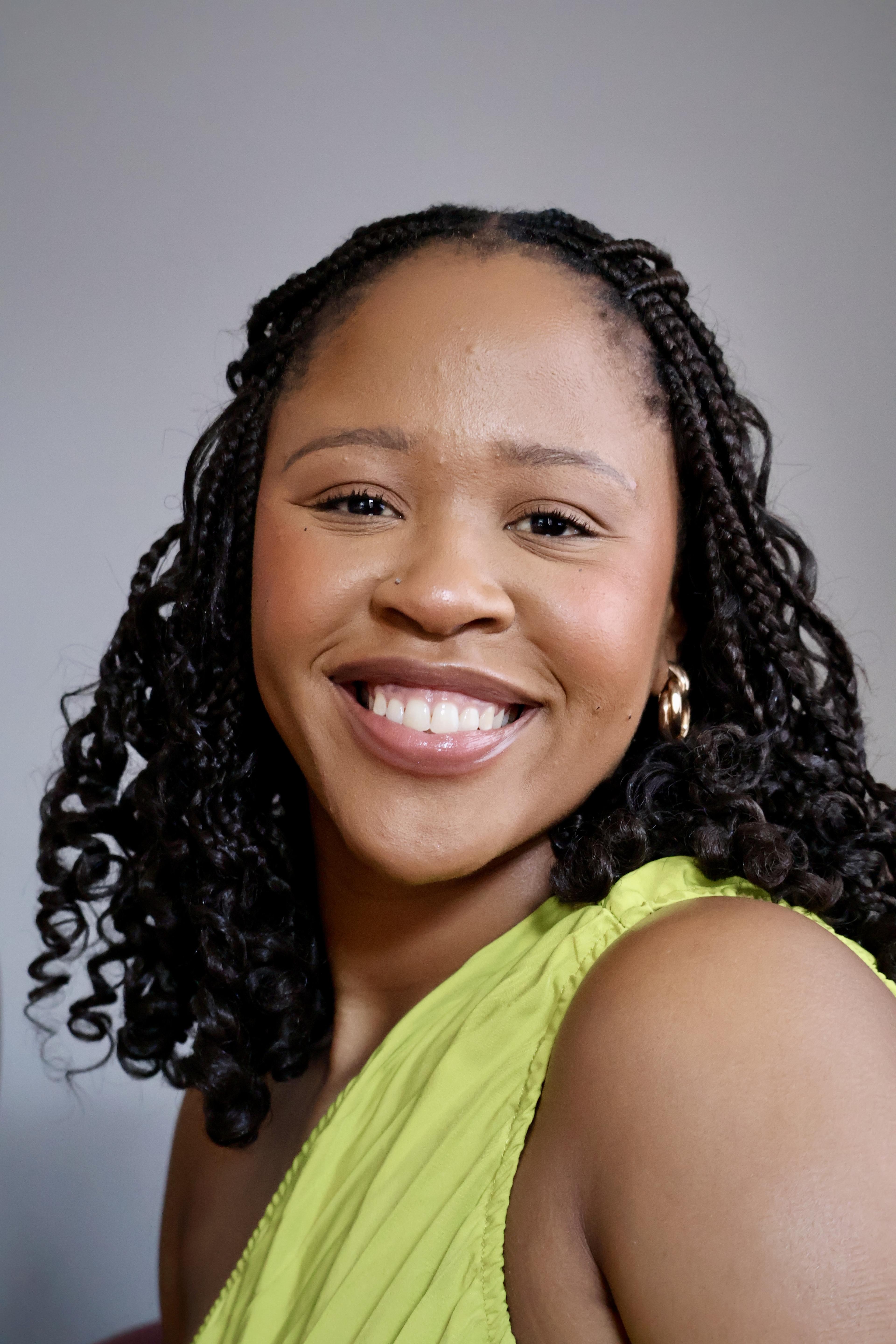 Smiling woman with braids in a bright green one-shoulder top
